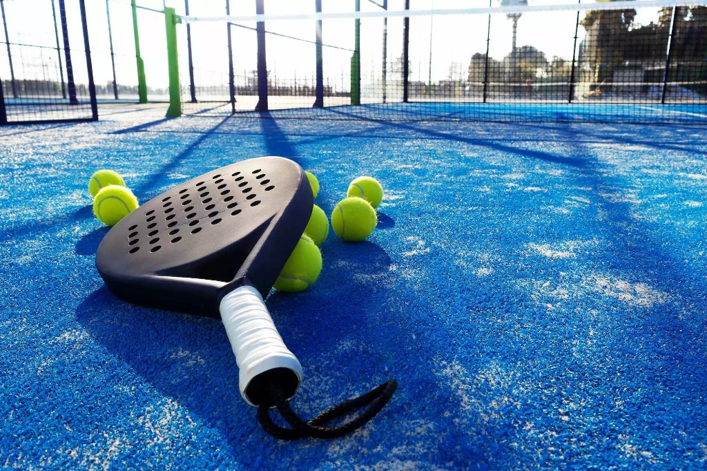 Padelracket en ballen op een blauwe padelcourt